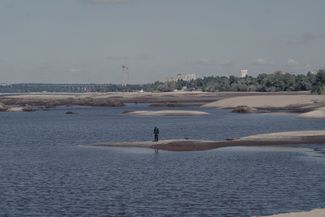 A man stands on one of the newly exposed sandbars in Zaporizhzhia