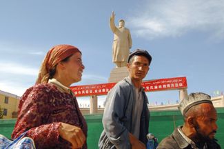 Уйгуры на Народной площади в Кашгаре, где установлена 20-метровая статуя Мао Цзэдуна, 16 августа 2009 года