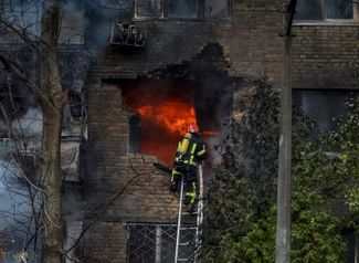 Пожарные тушат пожар в жилом доме в Киеве, пострадавшем от российского ракетного удара