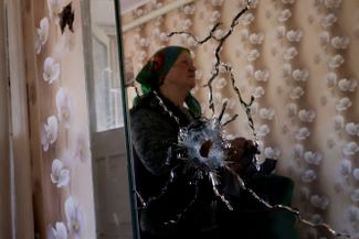 Жительница села Новотаврическое Запорожской области, частично оккупированной российскими войсками, показывает свой дом после обстрелов