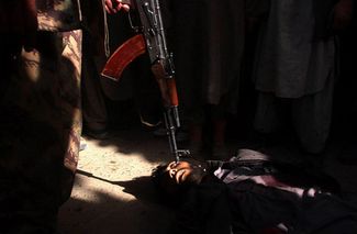 Солдат Северного альянса приставил оружие к голове боевика Талибана, убитого несколько минут назад в городе Кундуз, последнем оплоте талибов на севере Афганистана, освобожденного войсками Северного альянса. 26 ноября 2001 года
