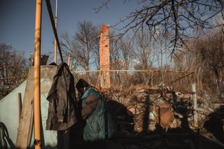 A Slatyne resident stands next to her destroyed home, where only the chimney and cellar remain