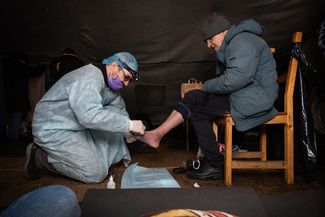 A “Charity Hospital” doctor examines unsheltered people in St. Petersburg at a “Nochlezhka” heating tent post in December 2019