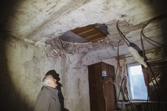 A Slatyne resident stands in an apartment damaged by shelling and bad weather