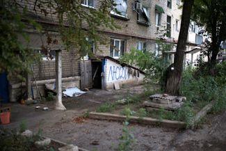 Поврежденный жилой дом в Северске. Судя по надписи на стене, в подвале укрываются мирные жители