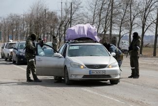 Men, presumably Russian soldiers, inspect the cars of Mariupol residents as they flee the city. March 20, 2022