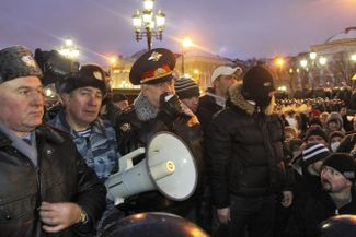 Начальник ГУВД Москвы Владимир Колокольцев (с мегафоном в центре) и загадочный человек в маске справа от него