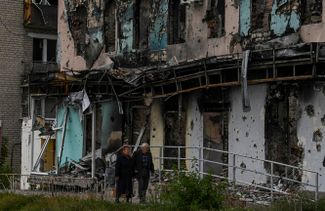 Жители Изюма на фоне разрушенного здания