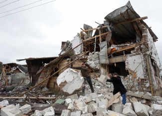 Жители поселка Глеваха разбирают завалы одного из домов, разрушенного в результате массированного обстрела 26 января