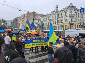 Гей-прайд в Киеве. Участники несут плакат в цветах украинского флага с текстом: «Вооружите Украину. Сделайте возможным прайд в Мариуполе». 16 июня 2024 года