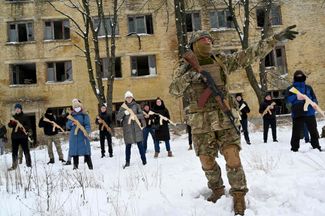 A military instructor and civilians with wooden replicas of Kalashnikov rifles at a training session in Kyiv. These sessions are led by instructors from the “Total Resistance” initiative, who have combat experience. Participants are taught combat tactics and proper first aid techniques.