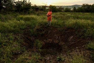 55-летняя Виктория возле воронки от снаряда, упавшего недалеко от ее сада. Они с мужем вернулись в Богородичное 23 мая