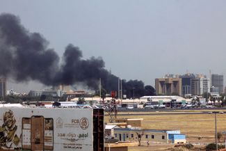 Дым над зданиями в районе аэропорта Хартума. 15 апреля 2023 года
