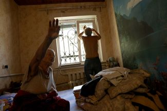 Жители села Руликов в спальне своей квартиры, где обломками российской ракеты выбило окно