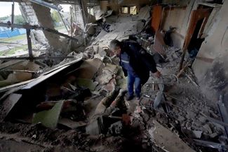 Украинский полицейский осматривает тело российского солдата в разрушенном кафе в недавно отвоеванном селе Петропавловка под городом Купянск Харьковской области