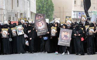Саудовские шиитские женщины держат плакаты с портретом убитого проповедника Нимр ан-Нимра на акции протеста 8 января 2016 года в городе Катиф.