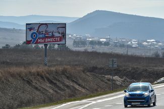 Автомобиль проезжает по дороге федерального значения А-291 «Таврида» под Симферополем мимо транспаранта с надписью «Девять лет вместе»