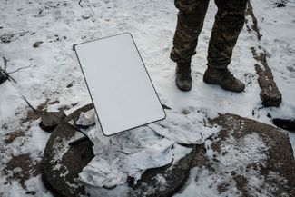 Украинский военнослужащий рядом с антенной спутникового интернета Starlink в Бахмуте