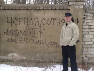 Anton Raevsky in Oryol. The wall behind him is covered in Black Hundred-themed graffiti.