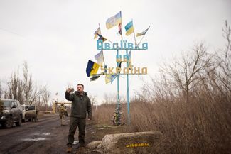 Владимир Зеленский записывает видеообращение на фоне дорожного знака «Авдiiвка це Украiна» («Авдеевка — это Украина») на въезде в город