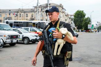 Украинский полицейский несет детские игрушки к месту российского ракетного удара, где создан стихийный мемориал. С утра 15 июля винничане несут к нему игрушки и цветы. В результате обстрела погибли трое детей четырех, семи и восьми лет, четверо детей пострадали