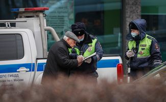 Сотрудник полиции останавливает пожилого мужчину за нарушение режима самоизоляции. Москва, 7 апреля 2020 года