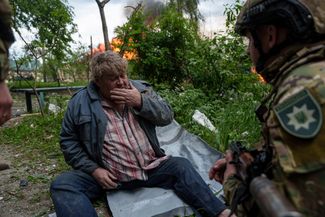 Украинский полицейский разговаривает с жителем Волчанска, потерявшим свой дом в результате российского авиаудара. Харьковская область, 11 мая 2024 года