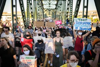 Протестующие идут по Хоторнскому мосту в Портленде, штат Орегон
