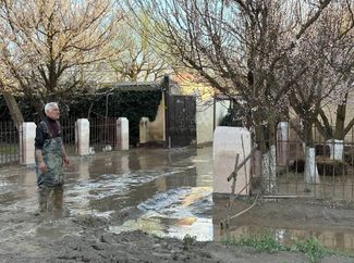 Another shot shows the aftermath of the first severe flood in Dagestan: A resident of the village of Adelotar in the Khasavyurt region stands on a flooded street. April 2