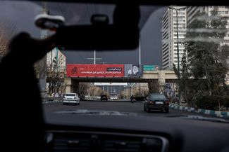 A banner depicting the assassinated Ayatollah Ali Khamenei in Tehran against a sky completely covered in smoke from the fires