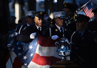 Пожарные Нью-Йорка с американским флагом, найденным после обрушения Всемирного торгового центра, в годовщину терактов 11 сентября. В результате атак в тот день погибли больше 300 нью-йоркских пожарных. 