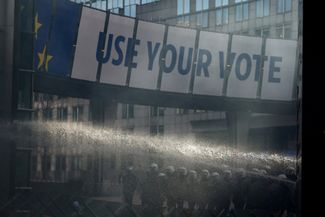 Сотрудники службы безопасности используют водомет возле здания Европарламента во время протестов фермеров из Бельгии и других европейских стран по поводу ценового давления, налогов и экологического регулирования в день саммита ЕС в Брюсселе. 1 февраля 2024 года