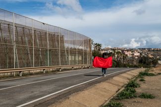 Мигрант идет вдоль забора, разделяющего Испанию и Марокко. 16 марта 2022 года, Мелилья (Испания)