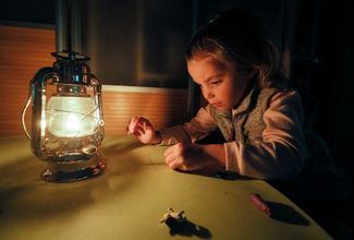Девочка лепит из пластилина при свете лампы в своей квартире в Киеве