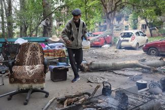 Мужчина готовит еду рядом со своим домом. Город находится под контролем самопровозглашенной ДНР