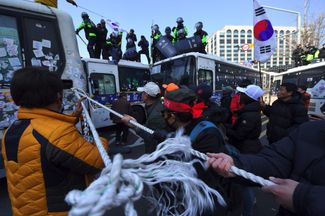 Протестующие двигают полицейский автобус, чтобы добраться до Конституционного суда Южной Кореи. 10 марта 2017 года