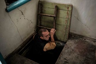 Житель Щурово Иван Лобанов вылезает из погреба. Дом его семьи пострадал от артобстрелов