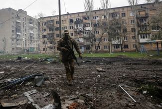 Украинский военнослужащий рядом с поврежденными жилыми домами