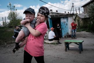 Девятилетняя Каролина держит на руках свою семимесячную сестру у входа в бункер в Лисичанске
