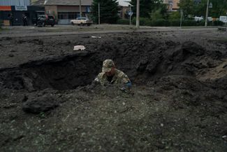 Украинский полицейский изучает место взрыва российских снарядов, чтобы определить, какими боеприпасами была совершена атака на Краматорск
