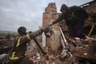 Житель Купянска передает спасателю сверток с вещами, найденными среди завалов на месте Краеведческого музея