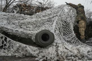 Украинский солдат снимает камуфляжную сетку с самоходной гаубицы 2С1 «Гвоздика»