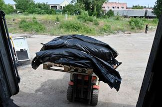 Эксгумированные под Харьковом тела российских солдат перед погрузкой в рефрижератор