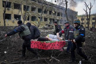 Украинские сотрудники МЧС выносят раненую беременную женщину из роддома, пострадавшего от обстрела. Мариуполь