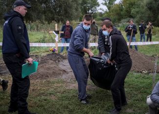 Мужчины несут тело жителя Балаклеи, который, согласно данным местной полиции, был убит российскими военными во время оккупации