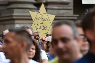 Участник акции протеста в Милане с желтой звездой наподобие тех, что нацисты заставляли носить евреев как отличительные символы. 24 июля 2021 года