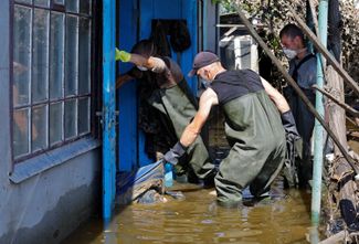 Еще один из 13 погибших жителей Голой Пристани, чье тело работники коммунальных служб достают из затопленного дома