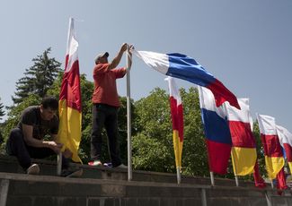 Мужчины прикрепляют флаги Южной Осетии и России в Цхинвали. 5 июля 2015-го