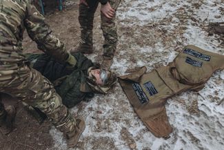 Украинские военные досматривают связанного российского пленного. 12 января 2023 года