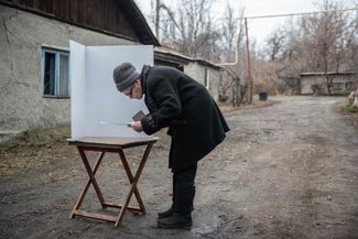 Женщина голосует на мобильном избирательном участке в Донецке